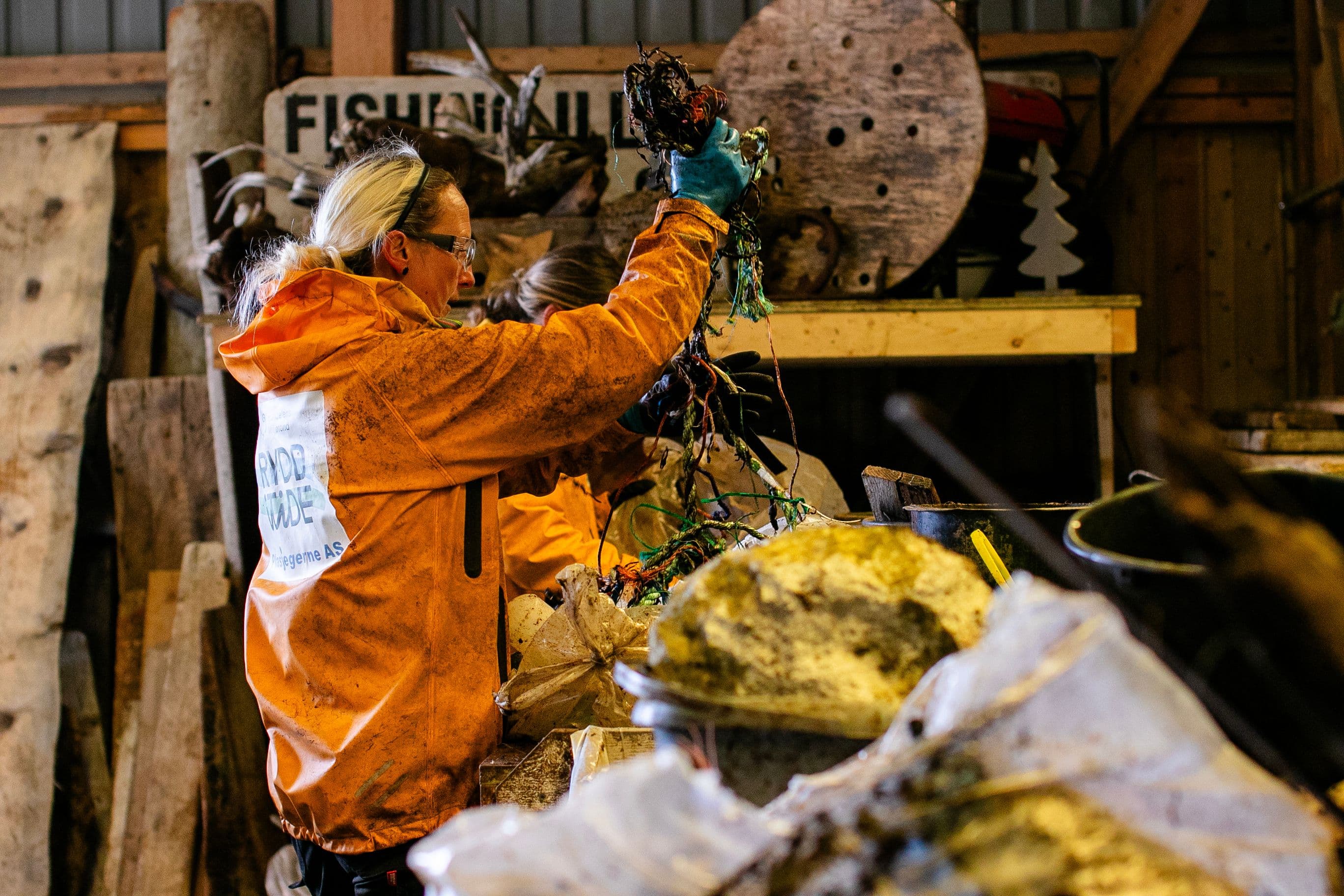 Woman in a Cleanup Norway in Time jacket sorting ropes and waste indoors